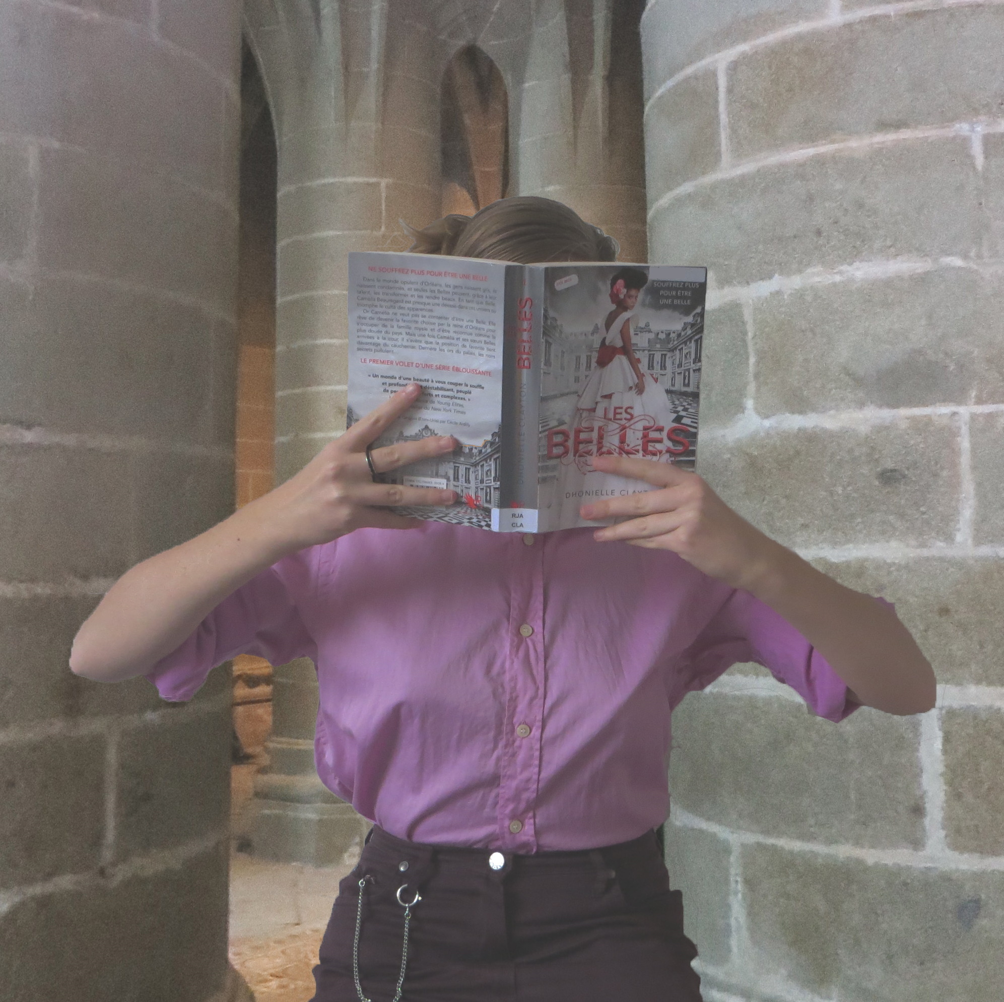 Femme en chemise rose lisant les Belles de Dhonielle Clayton dans des catacombes
