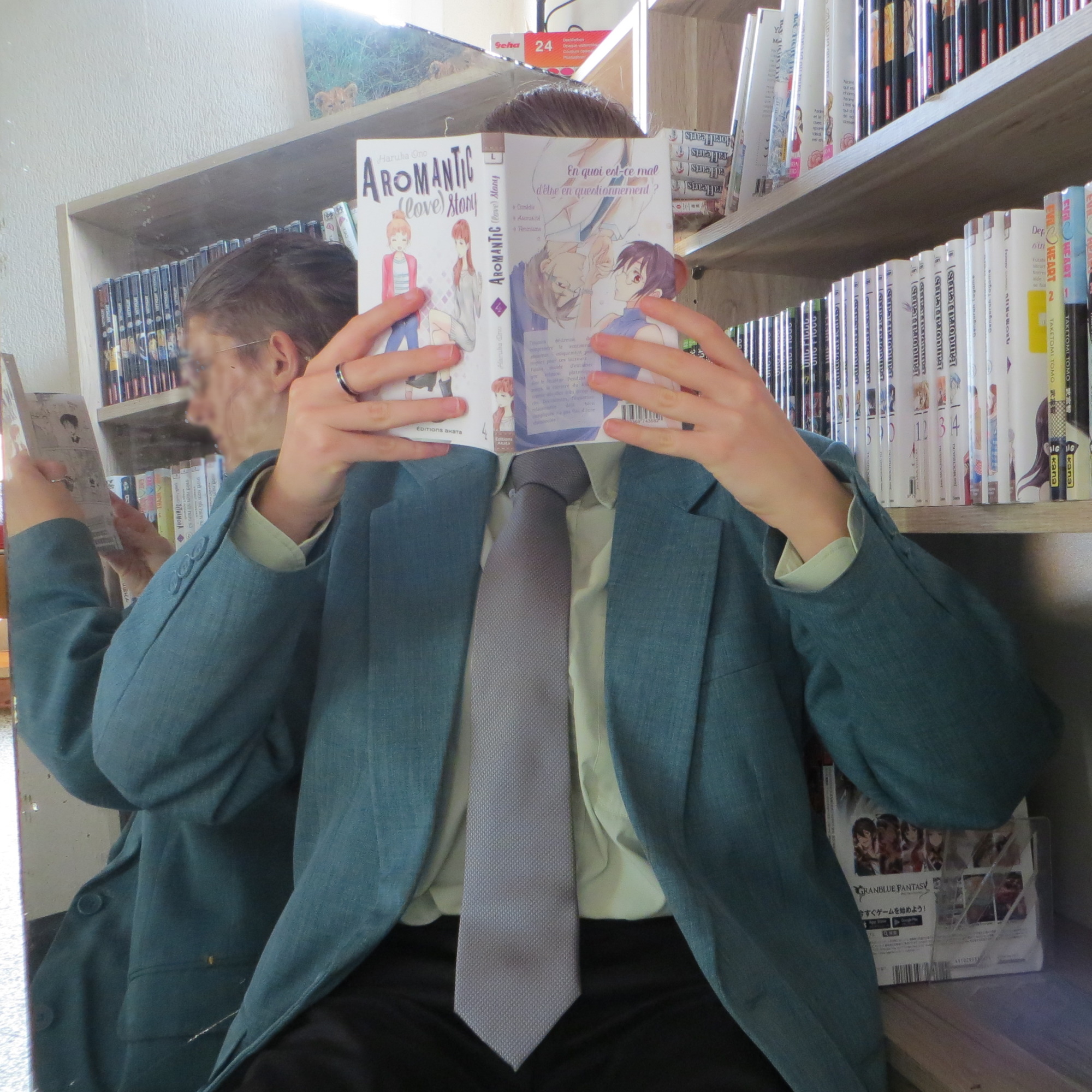 personne en costume aux couleurs aromantiques, lisant Aromantic Love Story de Haruka Ono entre une bibliothèque et un miroir