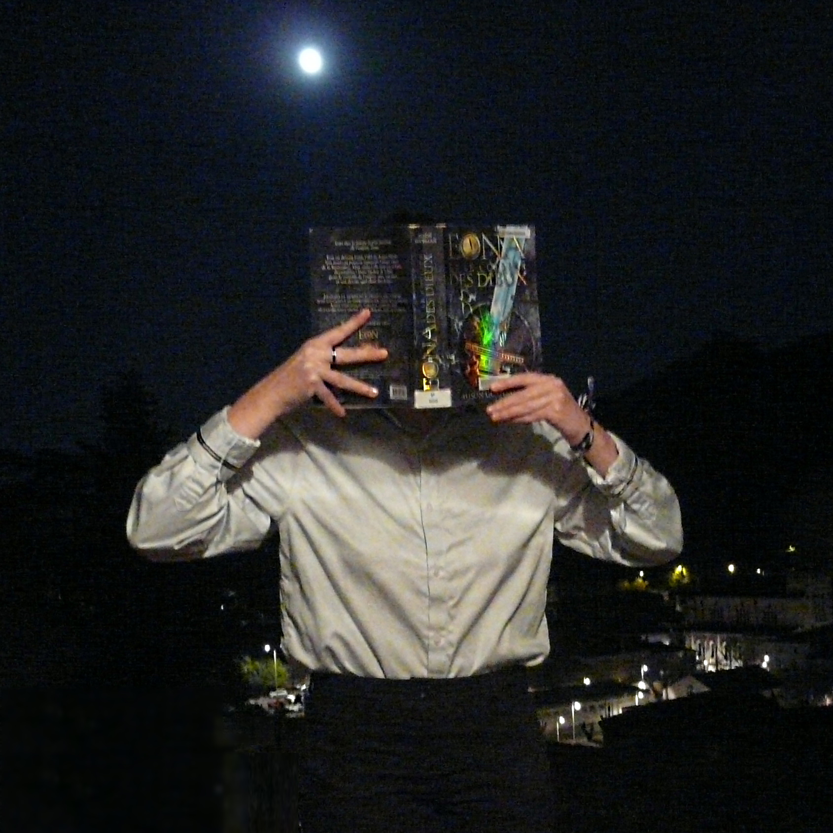 personne en chemise grise lisant Eona et le Collier des Dieux d'Alison Goodman de nuit, la lune en fond