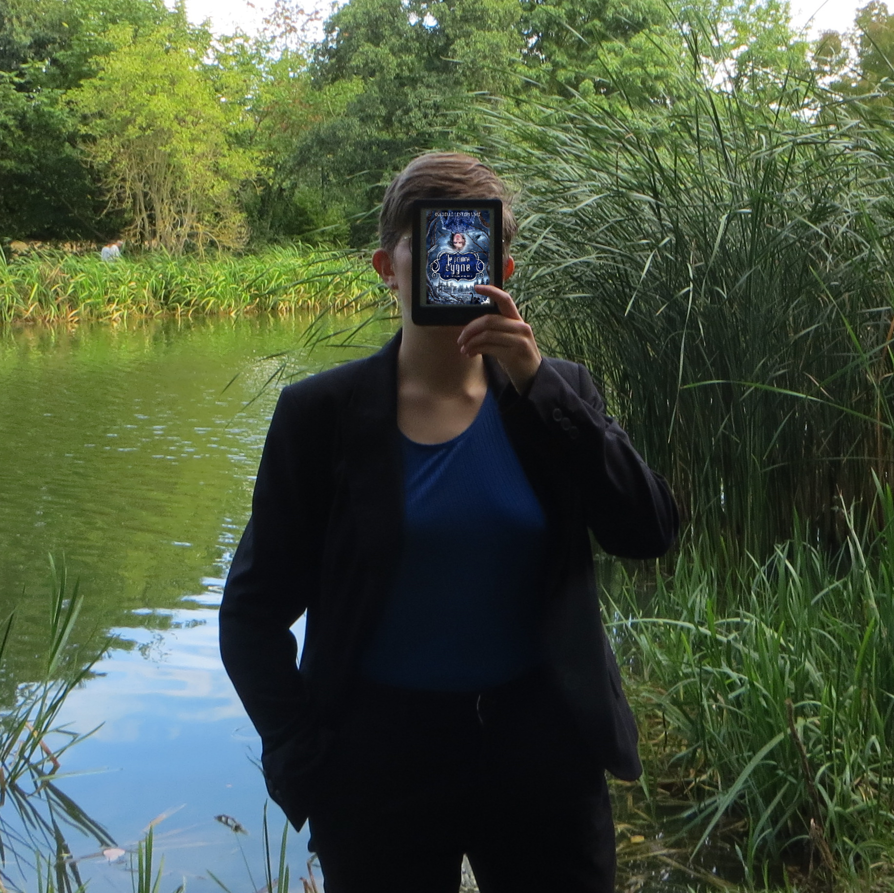 personne en débardeur bleu et veste noire lisant Le prince cygne d'Isabelle Lesteplume devant un lac