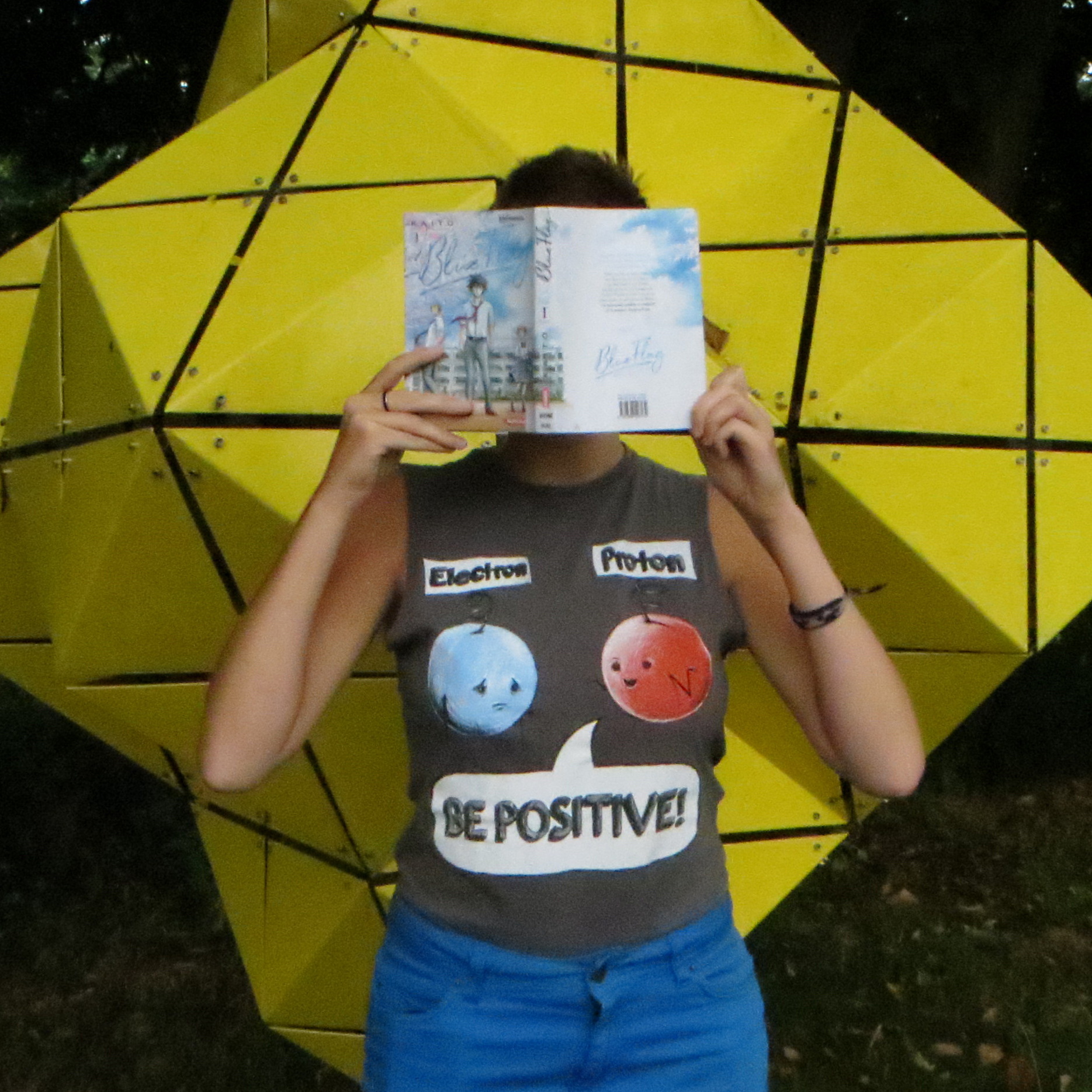 personne lisant Blue Flag de Kaito tome 1 devant une structure géométrique jaune