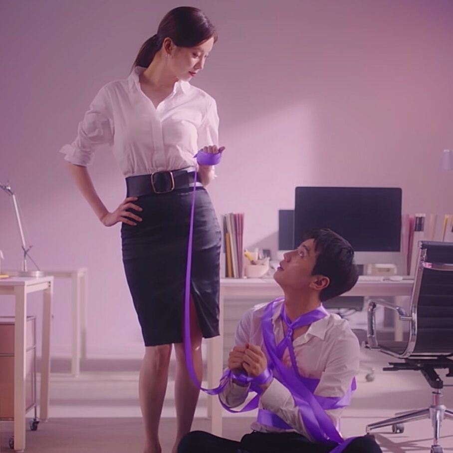 affiche de Love and Leashes, on y voit les personnages en tenue de travail, Jihoo est assis et attaché avec un ruban violet que Jiwoo, debout, tient