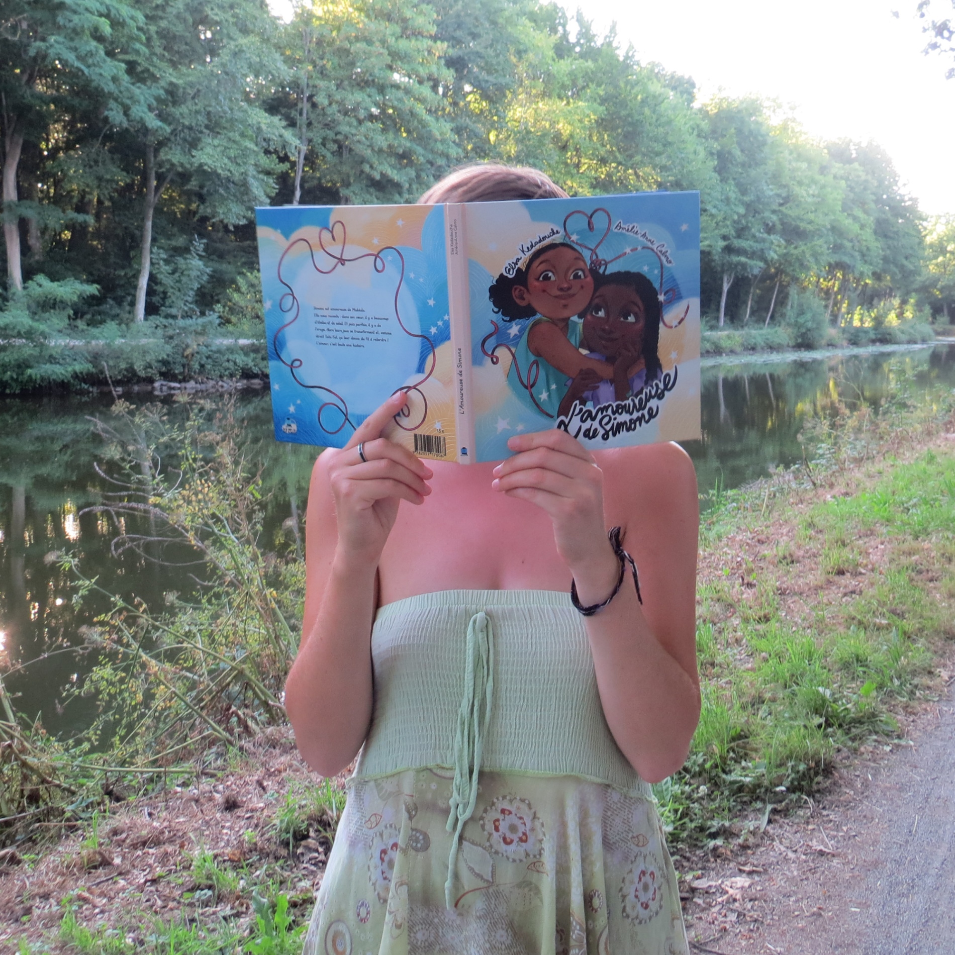 personne en robe verte lisant L’Amoureuse de Simone de Kedadouche Elsa & Amélie-Anne Calmo devant une rivière