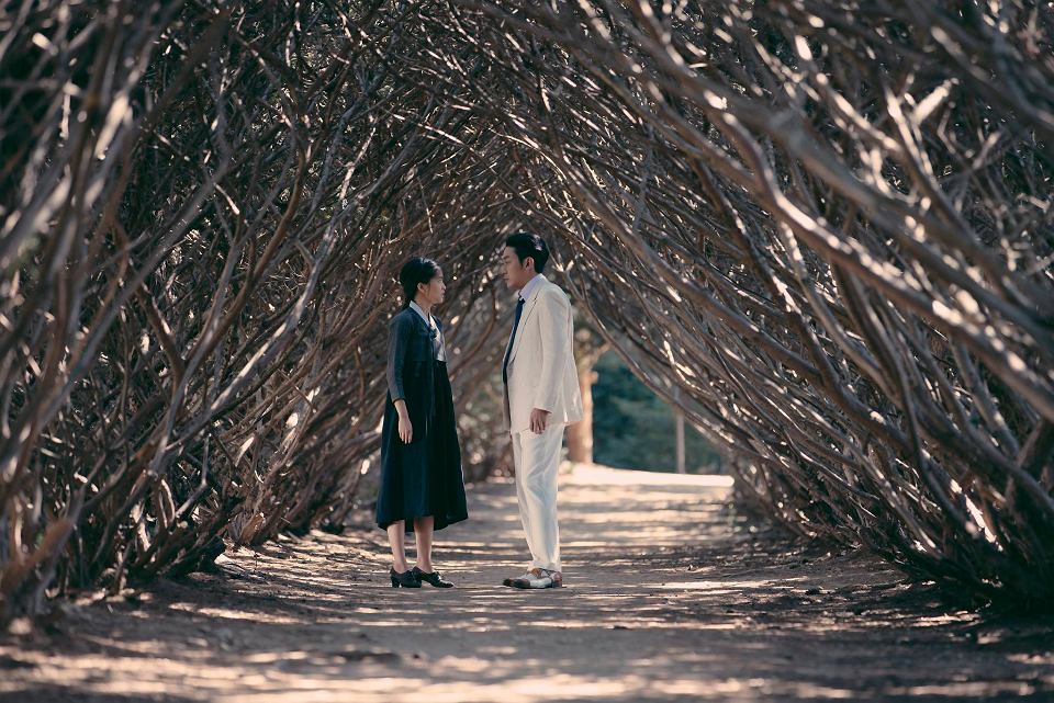 capture d'écran du film The Handmaiden, deux personnages discutent sur un chemin entouré de buissons nus symétriques formant une sorte de toit