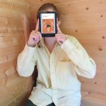 personne en large chemise jaune lisant Sauvagines de Gabrielle Filteau-Chiba dans le coin d'un bâtiment en planches de bois